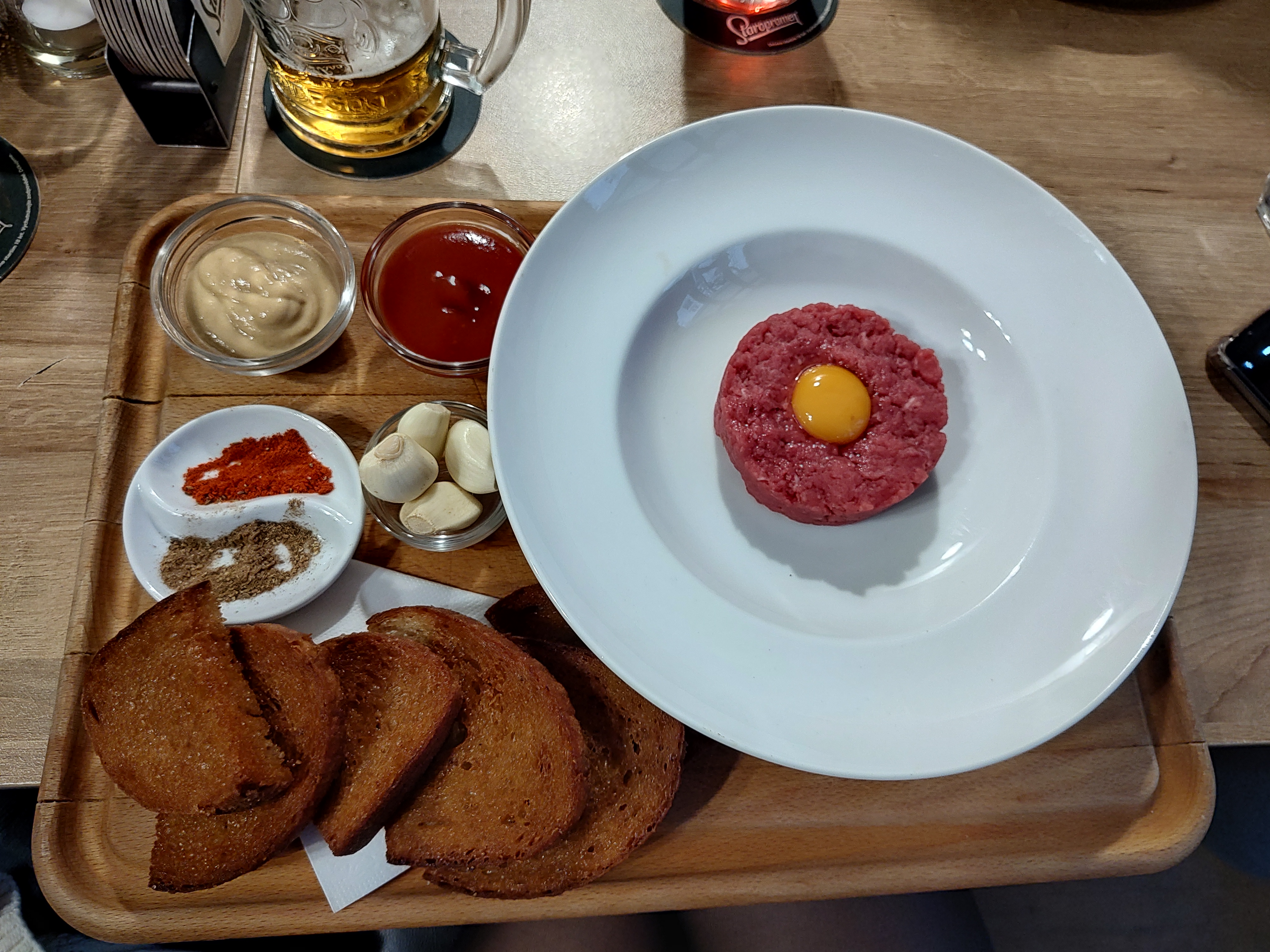 Cómo se sirve el tatarák en Praga, carne cruda picada con yema de huevo y especias al lado
